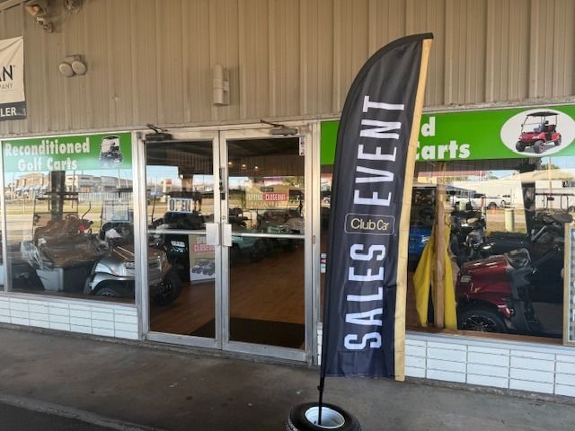 Storefront entrance with glass doors and a black “Sales Event” flag sign outside.