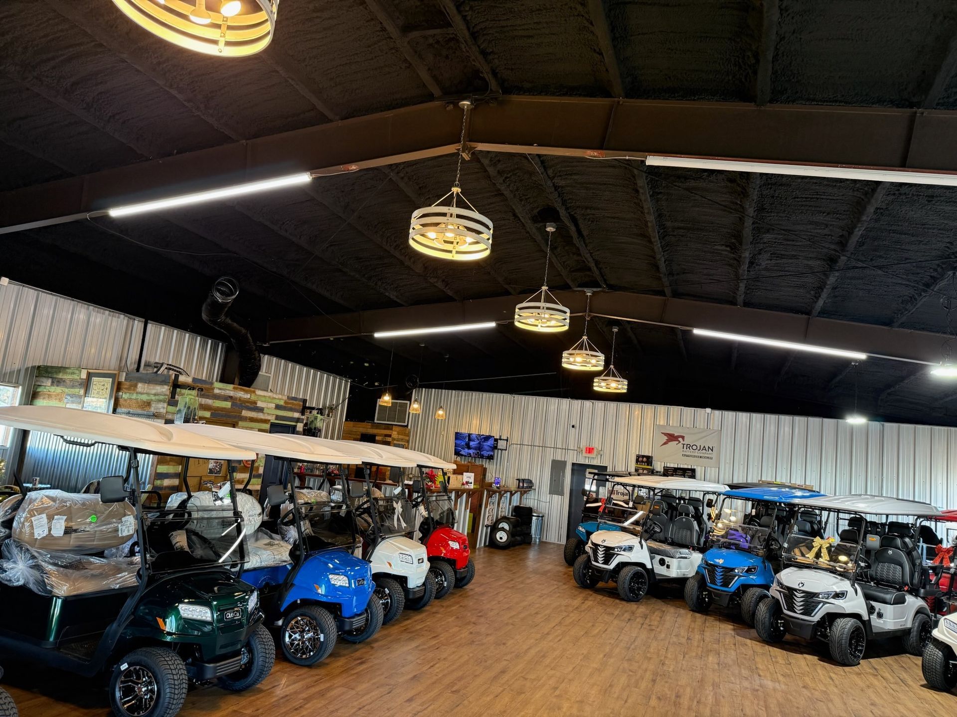 Indoor showroom with rows of blue and white golf carts under hanging lights