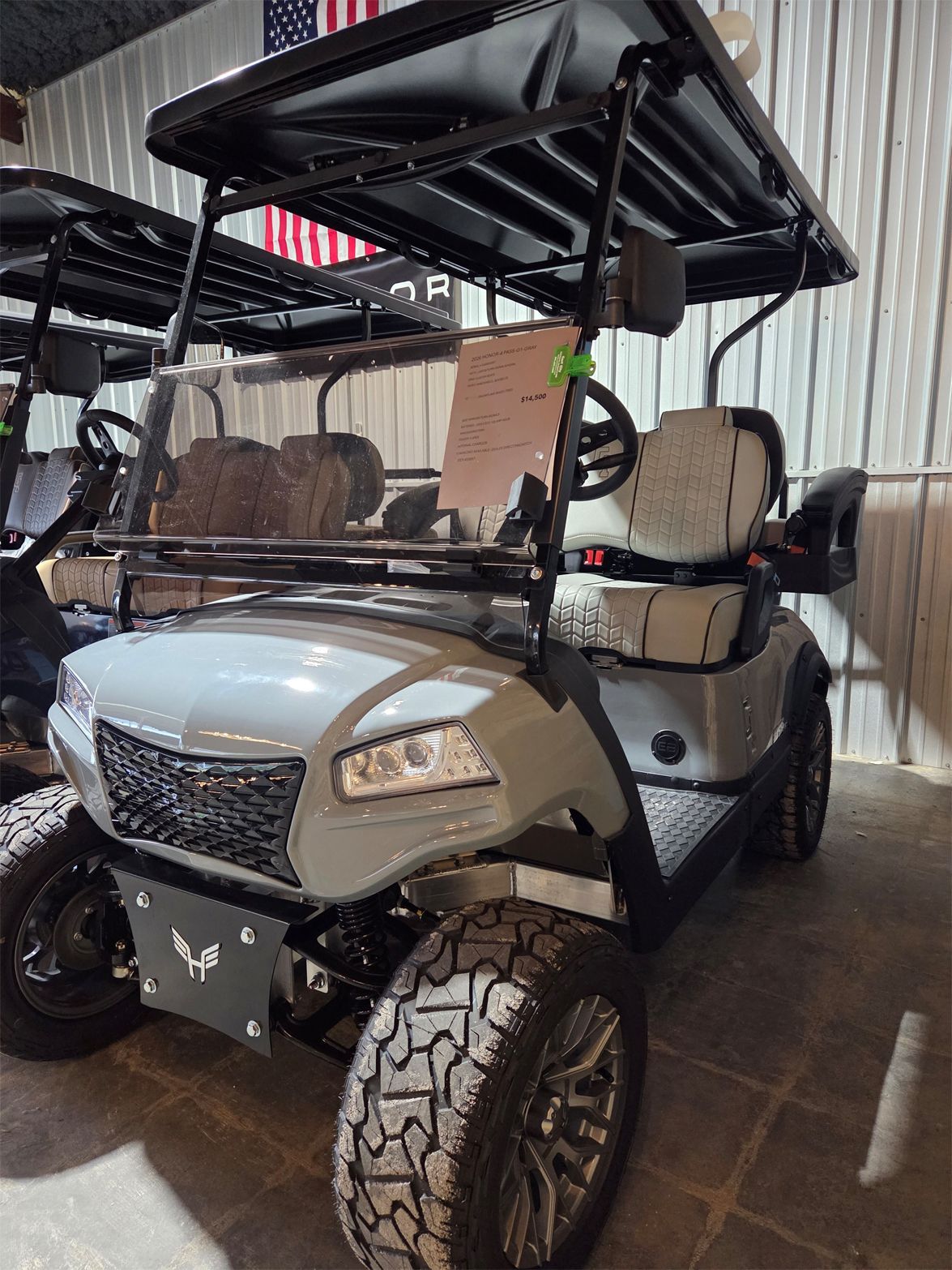 Gray golf cart with roof and off-road tires parked indoors.