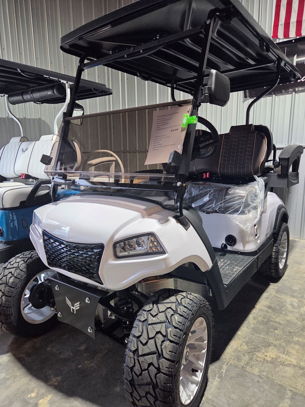 White golf cart with black canopy parked indoors in a garage or showroom.