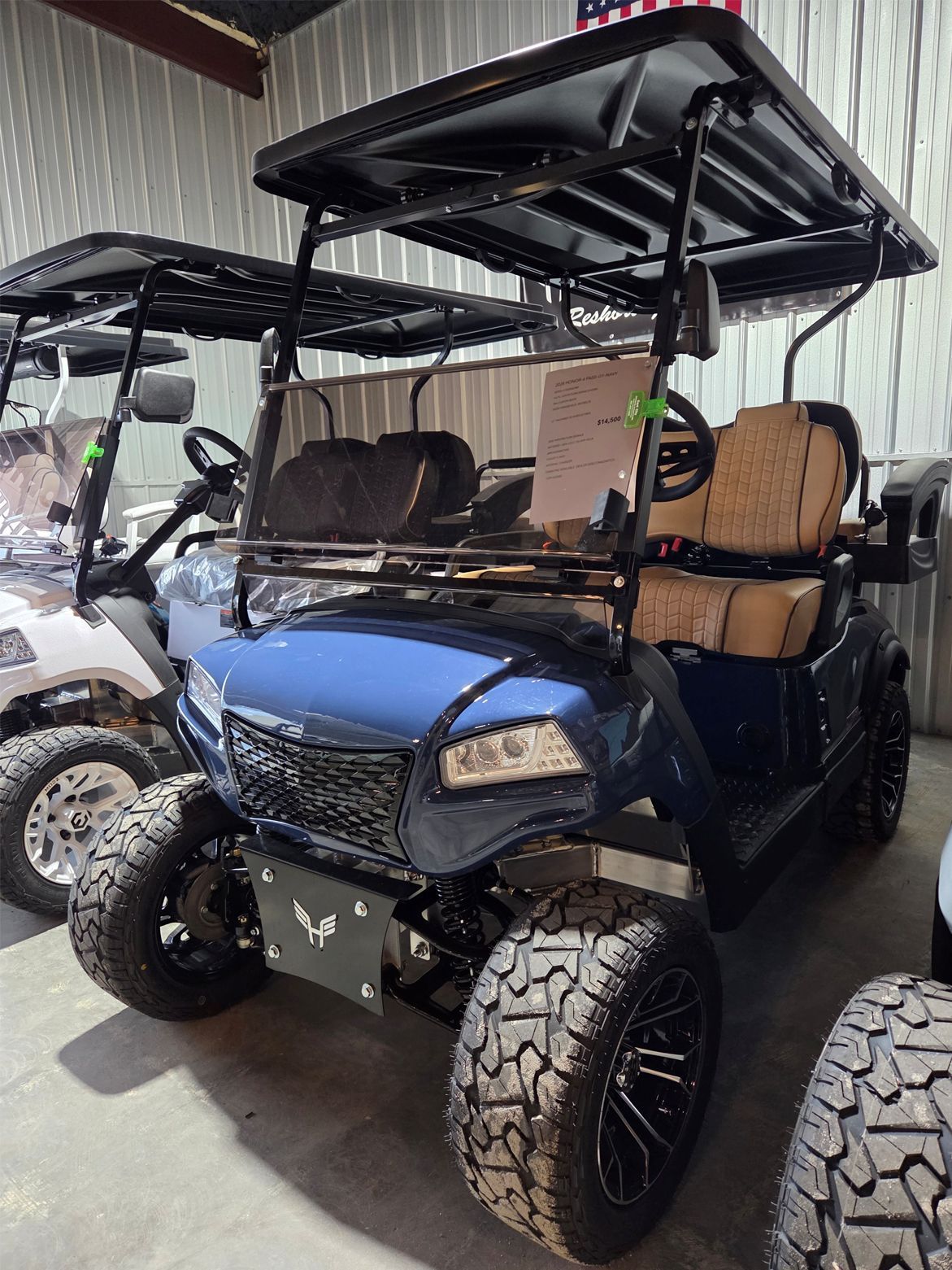 Blue off-road golf cart with tan seats and roof in a showroom