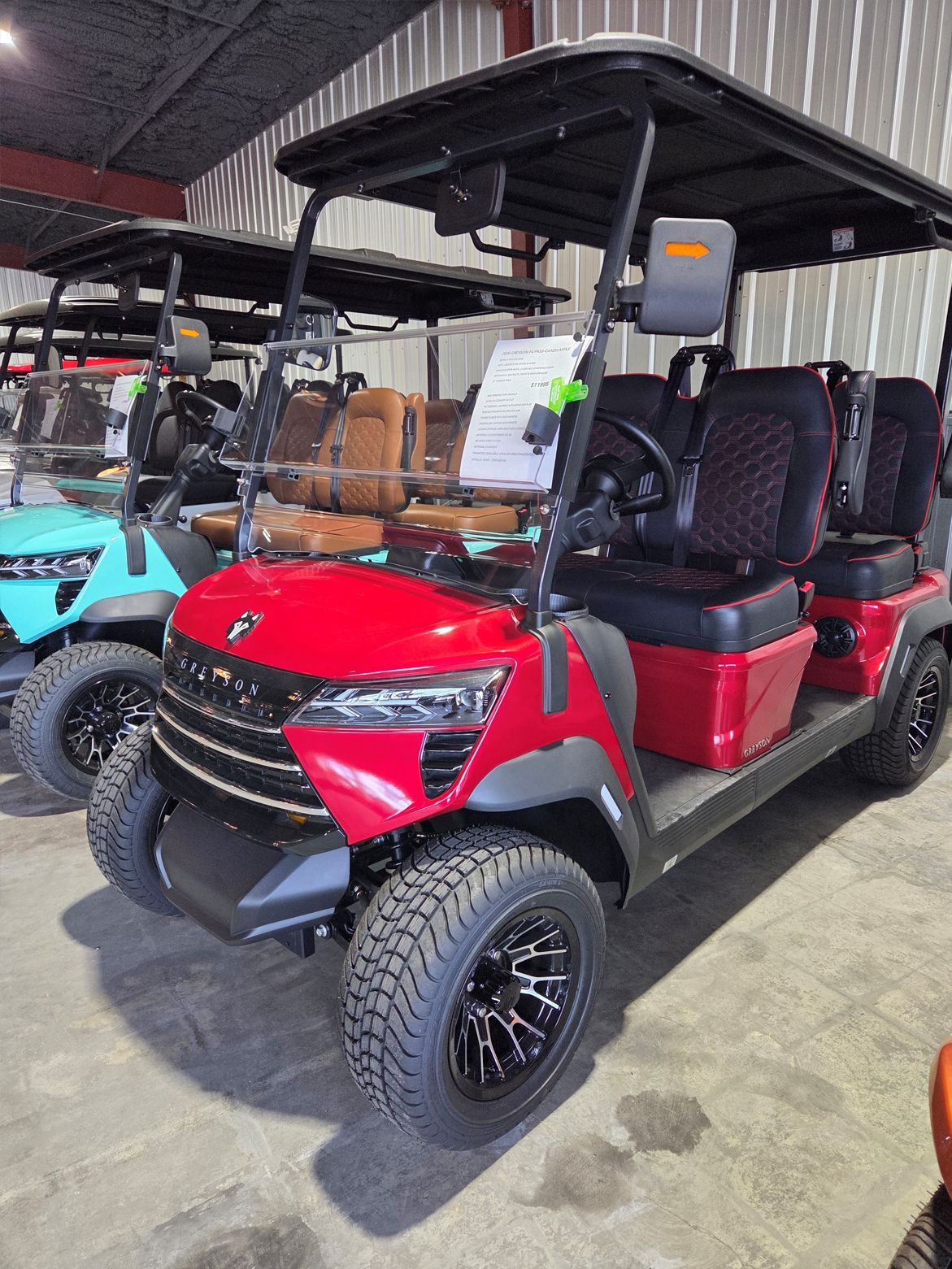 Red golf cart with black roof and off-road tires parked indoors on a showroom floor