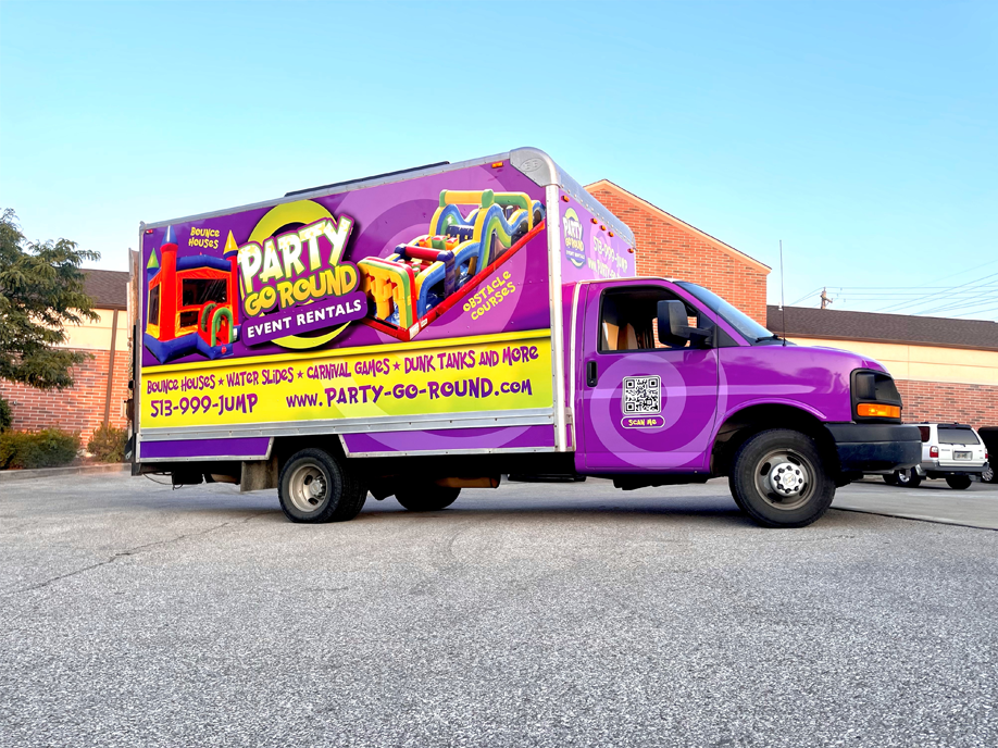 A purple Party Go Round truck is parked on the side of the road.
