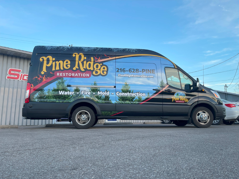 A pine ridge restoration van is parked in front of a building.