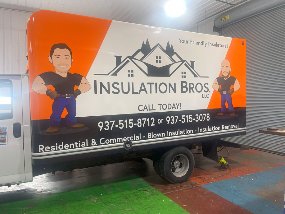 An insulation bros truck is parked in a garage.