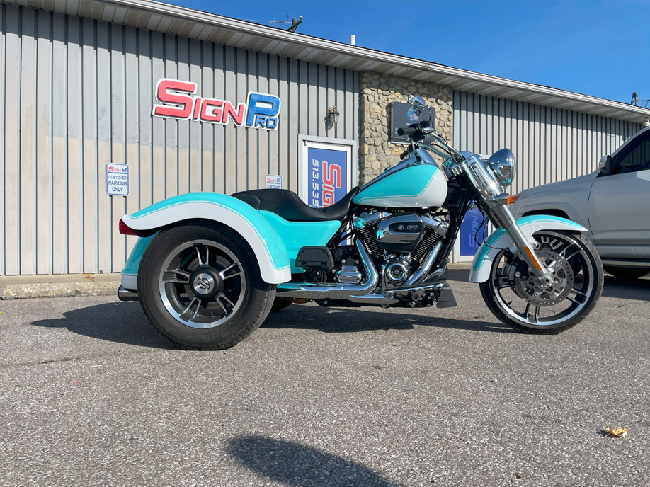 A motorcycle with three wheels is parked in front of a building.