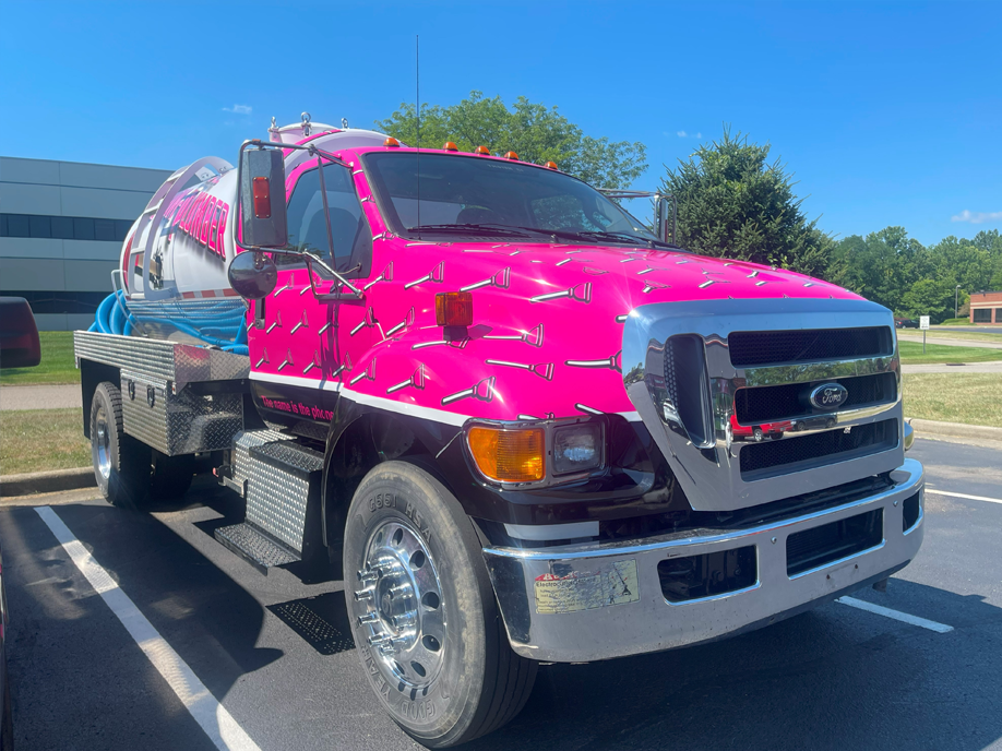 A pink truck is parked in a parking lot.