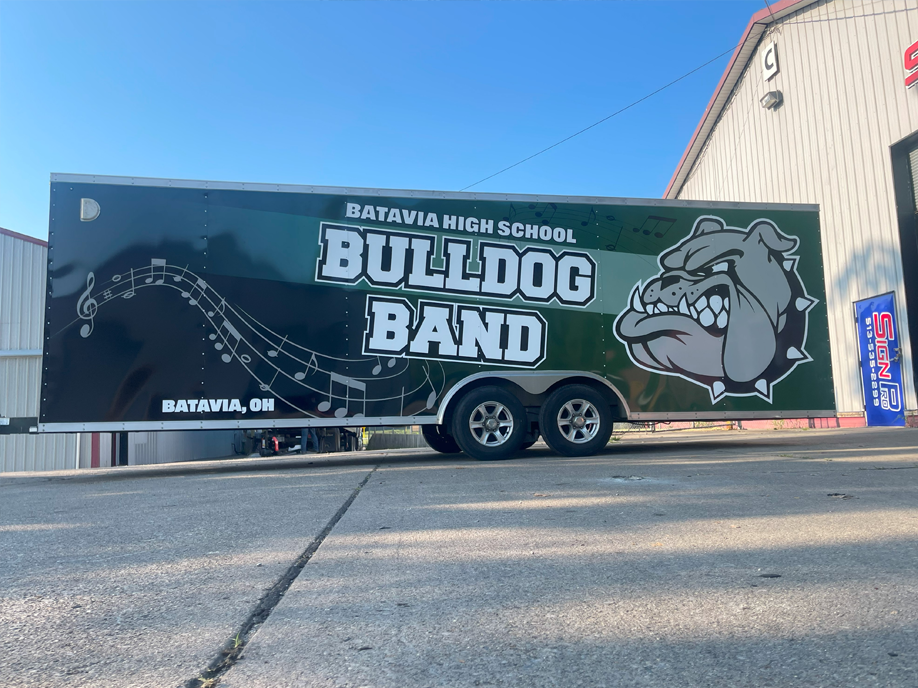 A bulldog band trailer is parked in front of a building.
