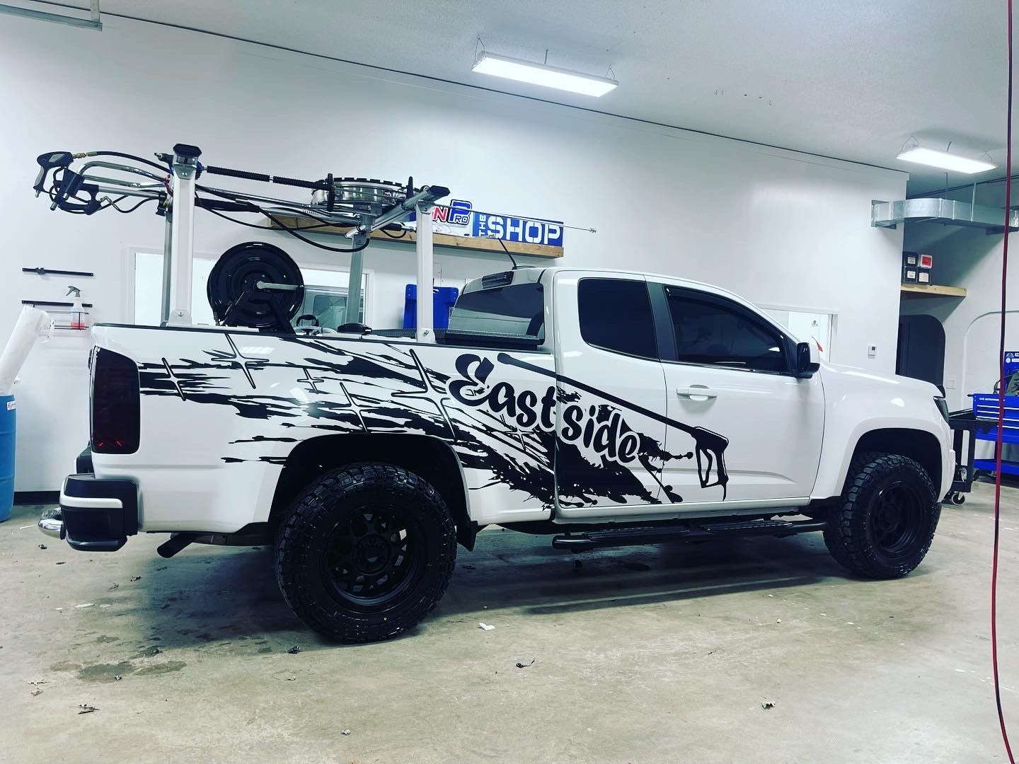 A white truck with east side written on the side is parked in a garage