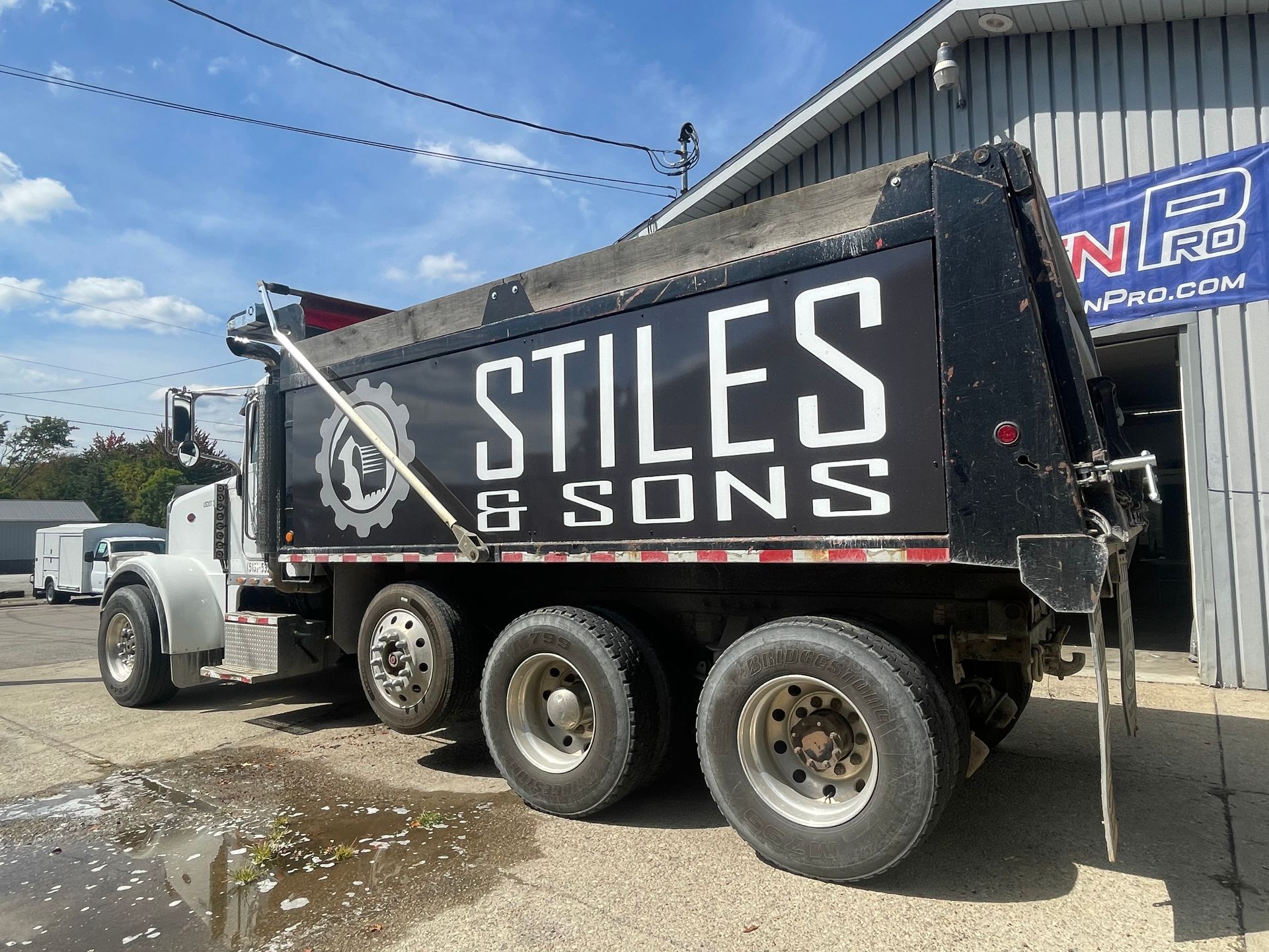 A stiles & sons dump truck is parked in front of a building