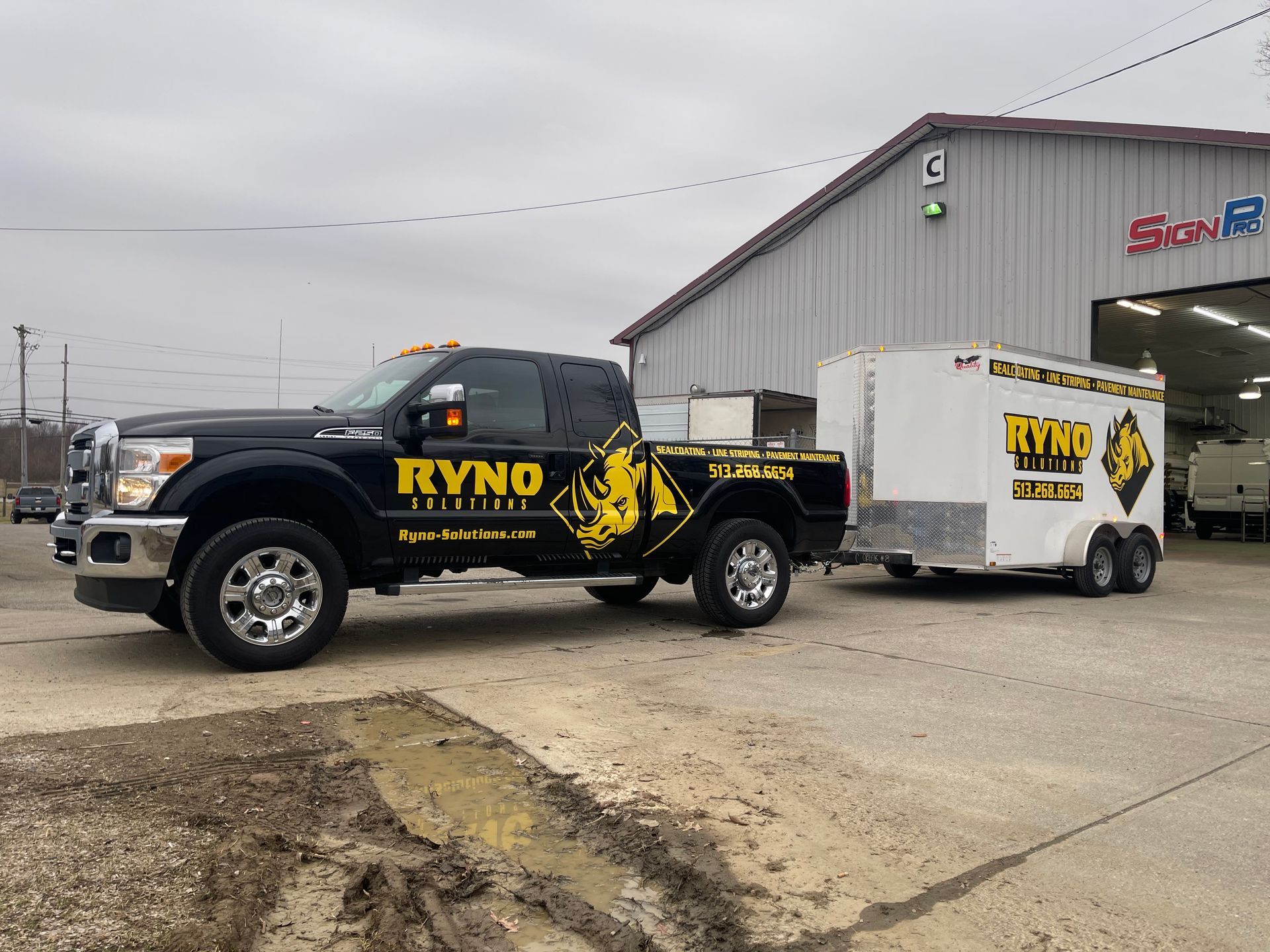 A truck with a trailer attached to it is parked in front of a building.