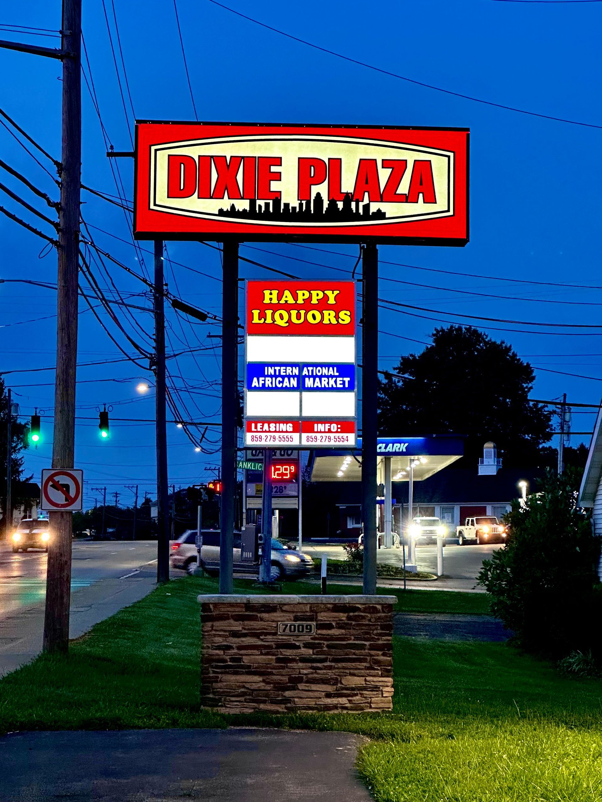 A sign for dixie plaza happy liquors is lit up at night