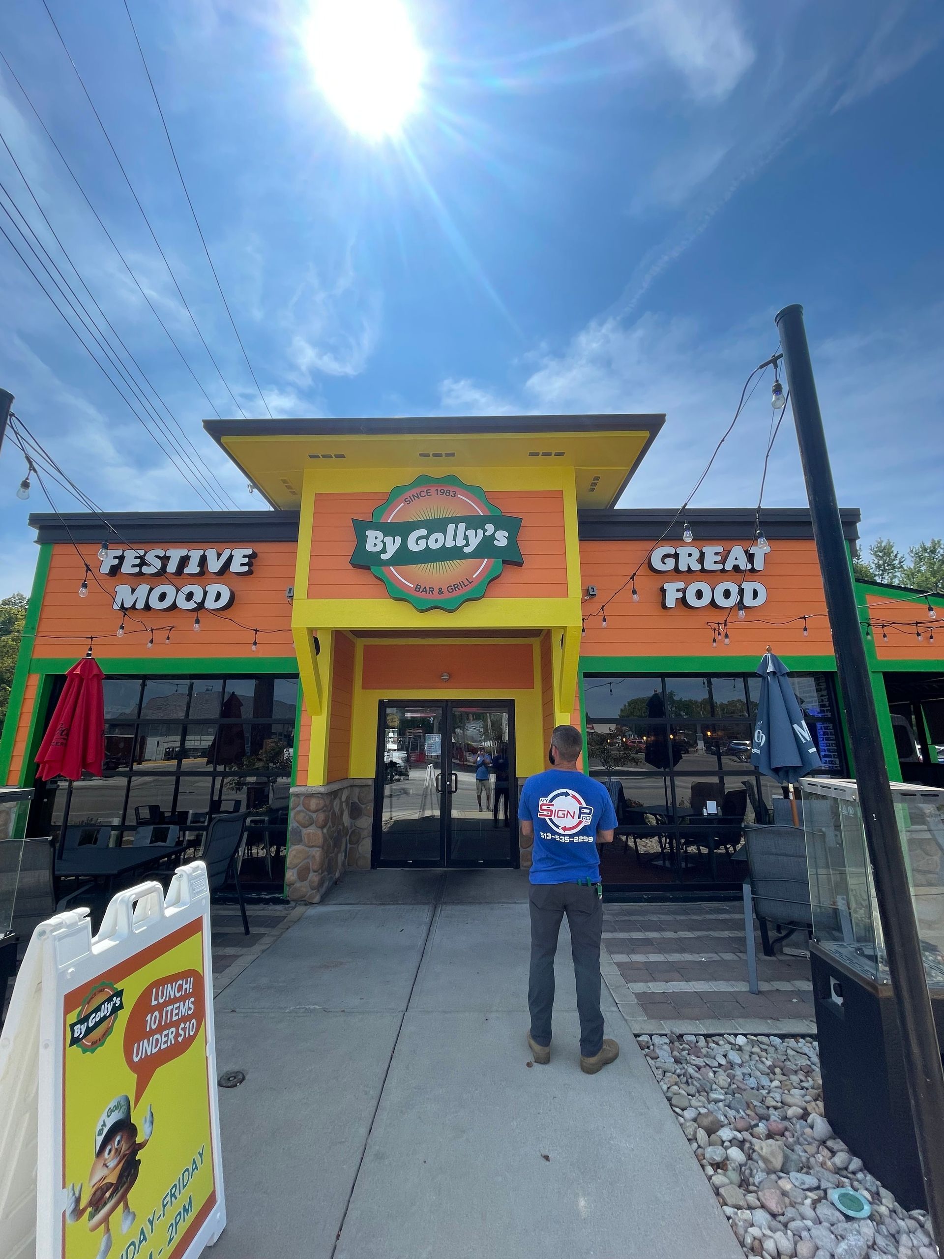 A man in a blue shirt is standing in front of a restaurant.