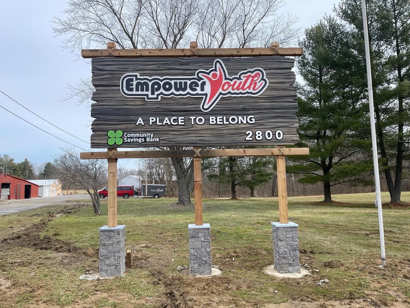 A wooden sign that says empower youth a place to belong