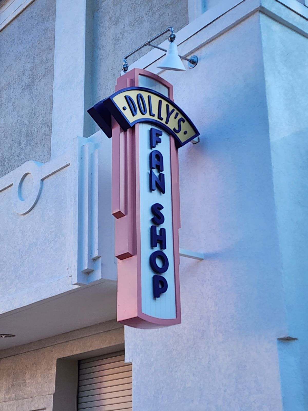 A sign for dolly 's fan shop hangs from the side of a building