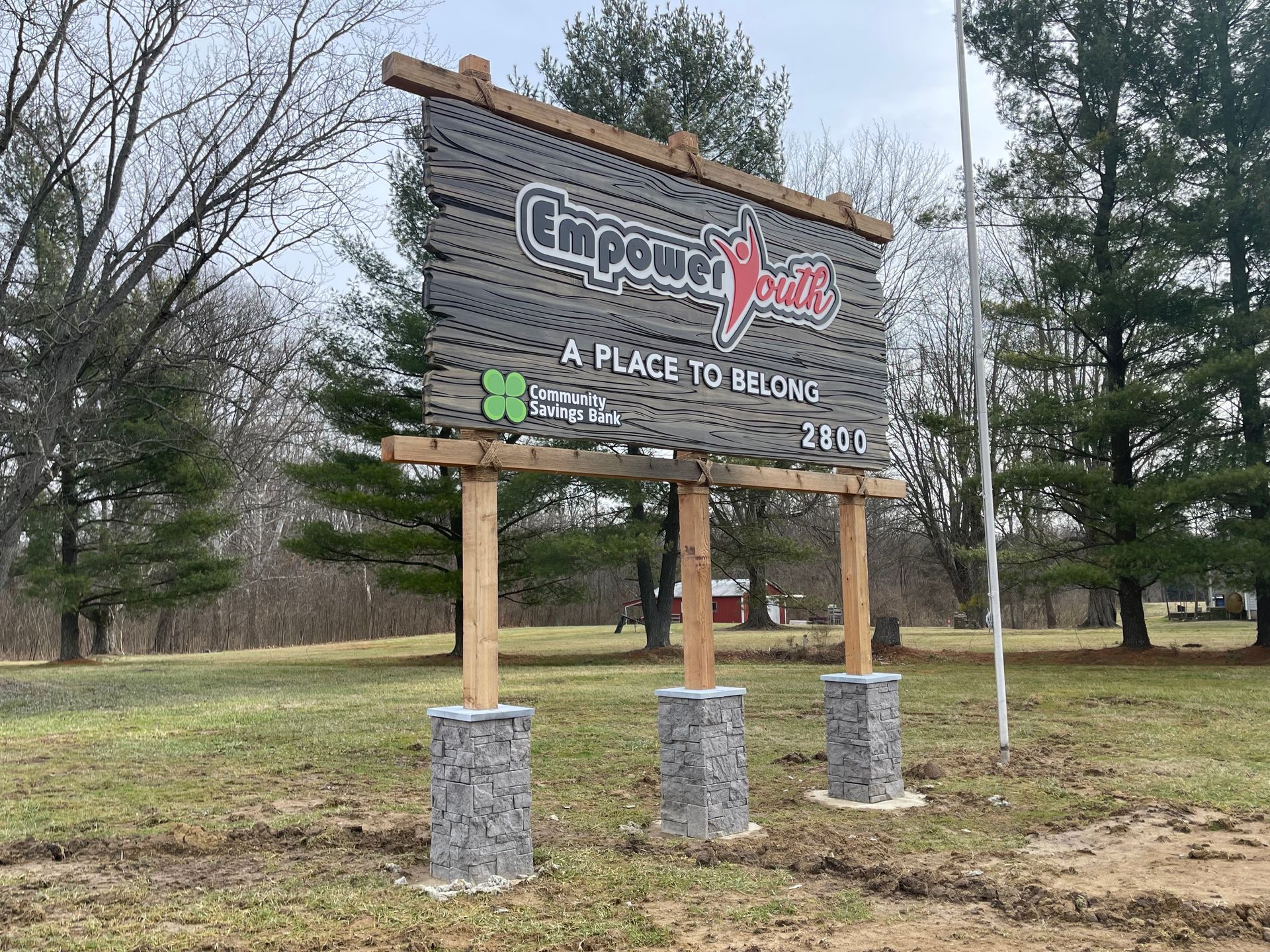 A large wooden sign is sitting in the middle of a grassy field.