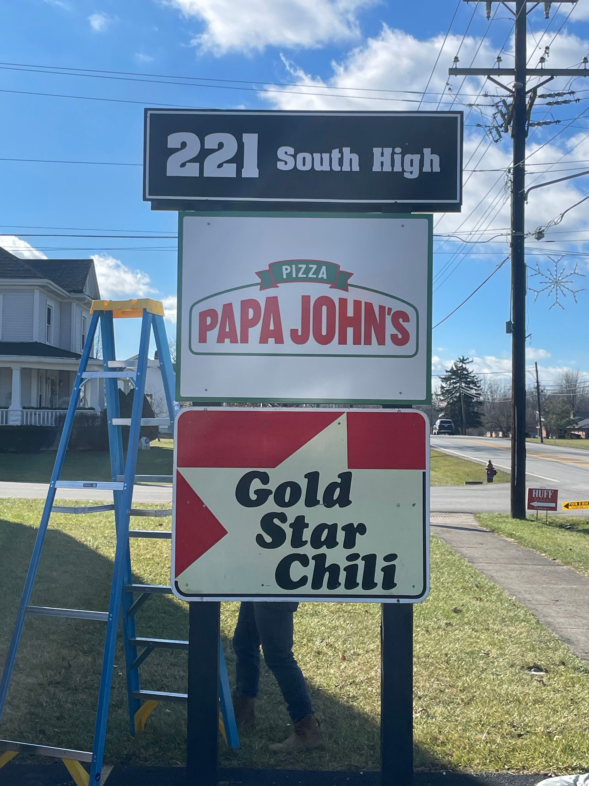 A sign for papa john 's gold star chili is being installed