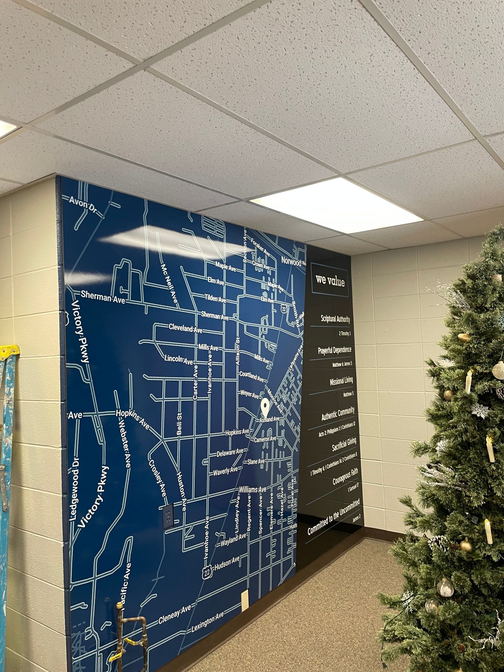 A hallway with a christmas tree and a large map on the wall