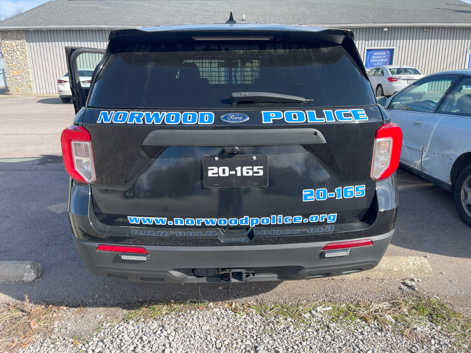 A black police car is parked in a parking lot.