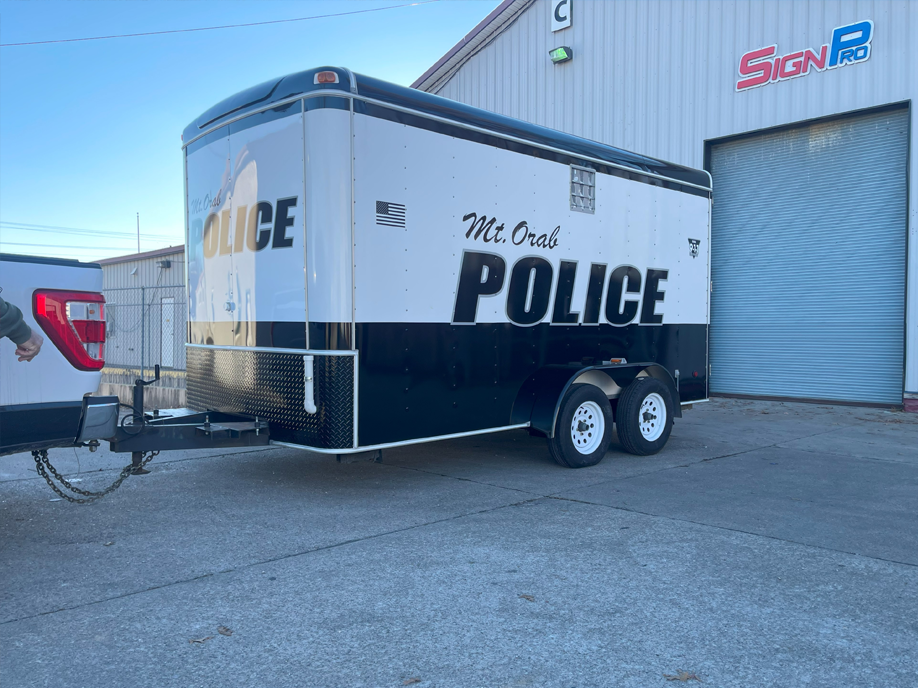 A police trailer is parked in front of a building.