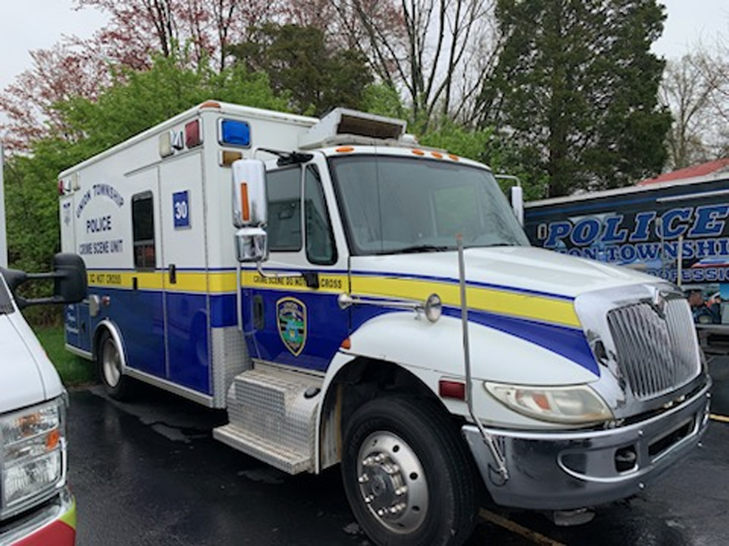 A blue and white police ambulance is parked in a parking lot.