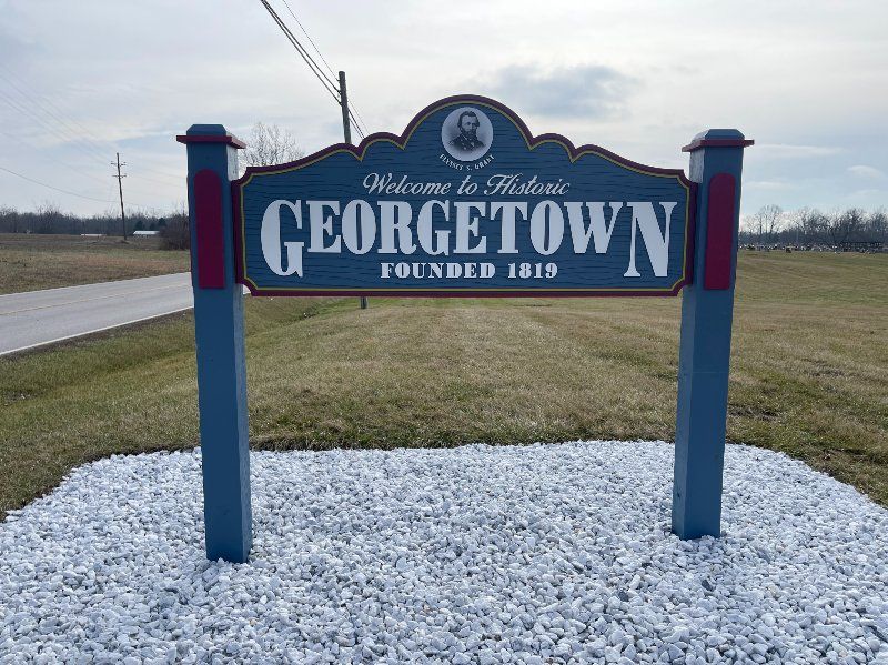 A welcome to georgetown sign is sitting on top of a pile of gravel.