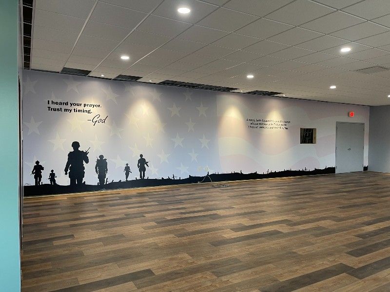 A large empty room with a mural on the wall and a wooden floor.