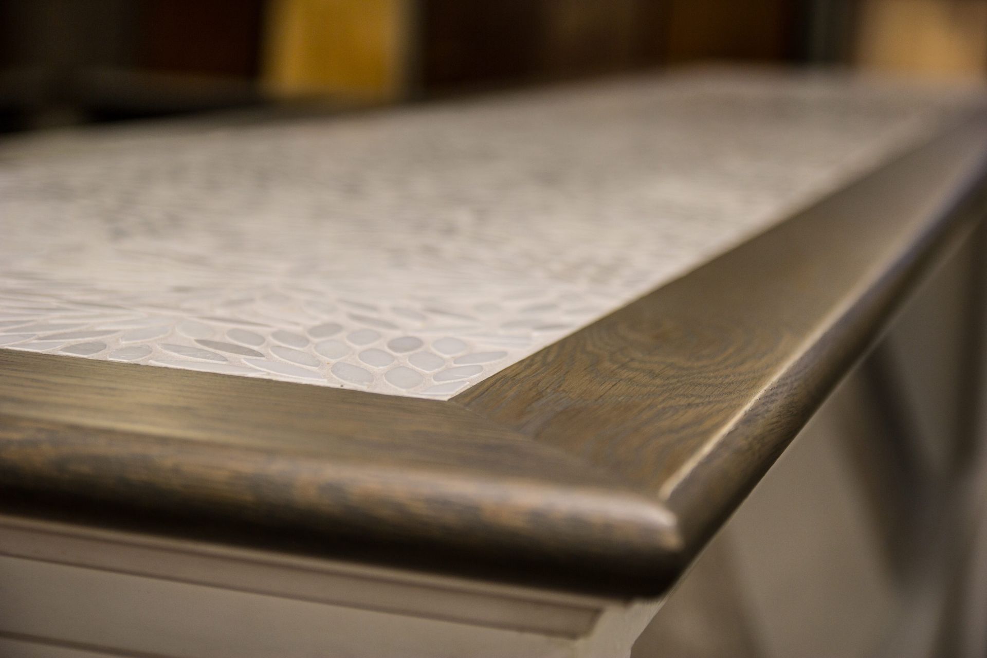 Close-up of a countertop with a light, patterned surface and a dark, rounded edge.