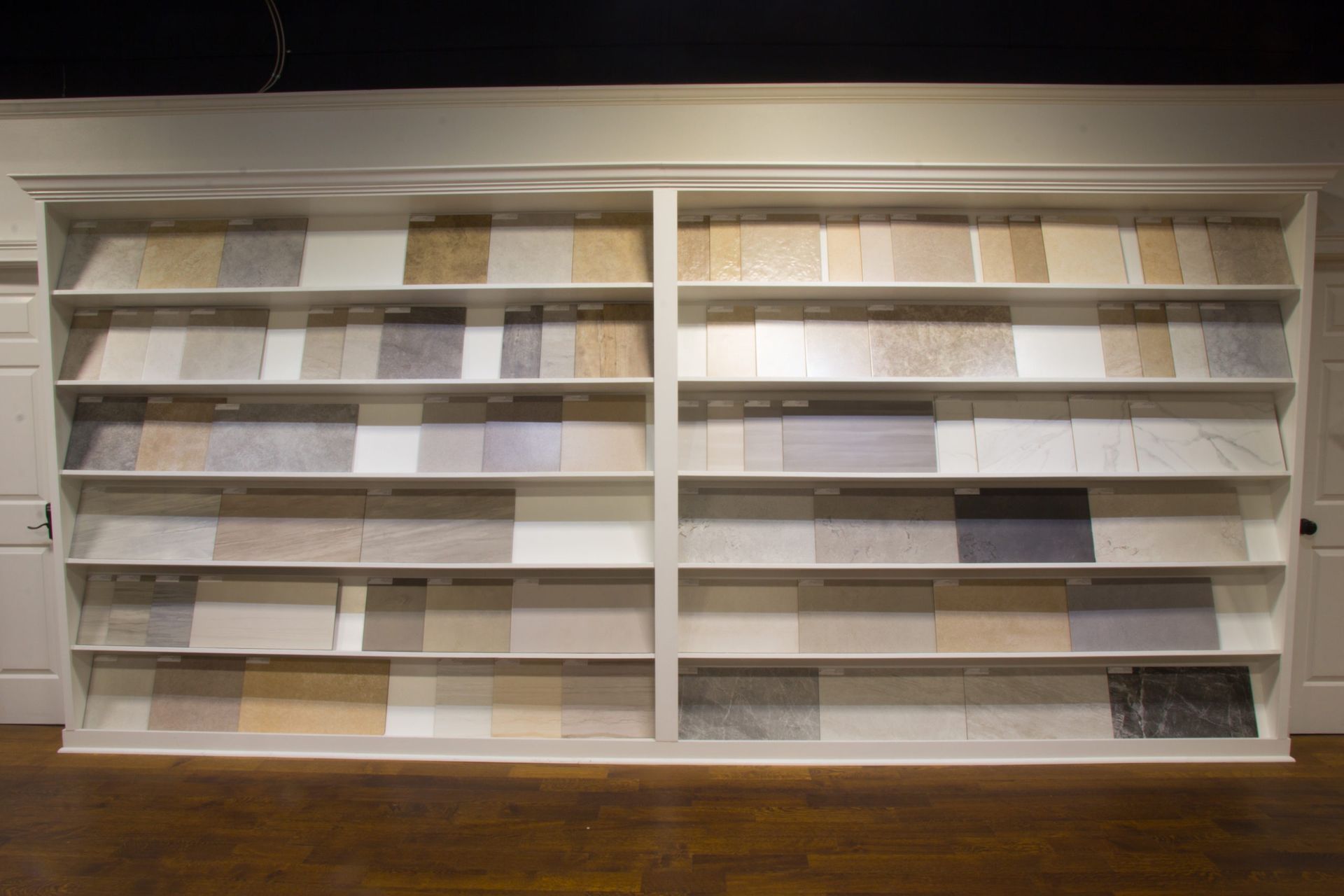 Display shelves showcasing various tile samples in a showroom setting.
