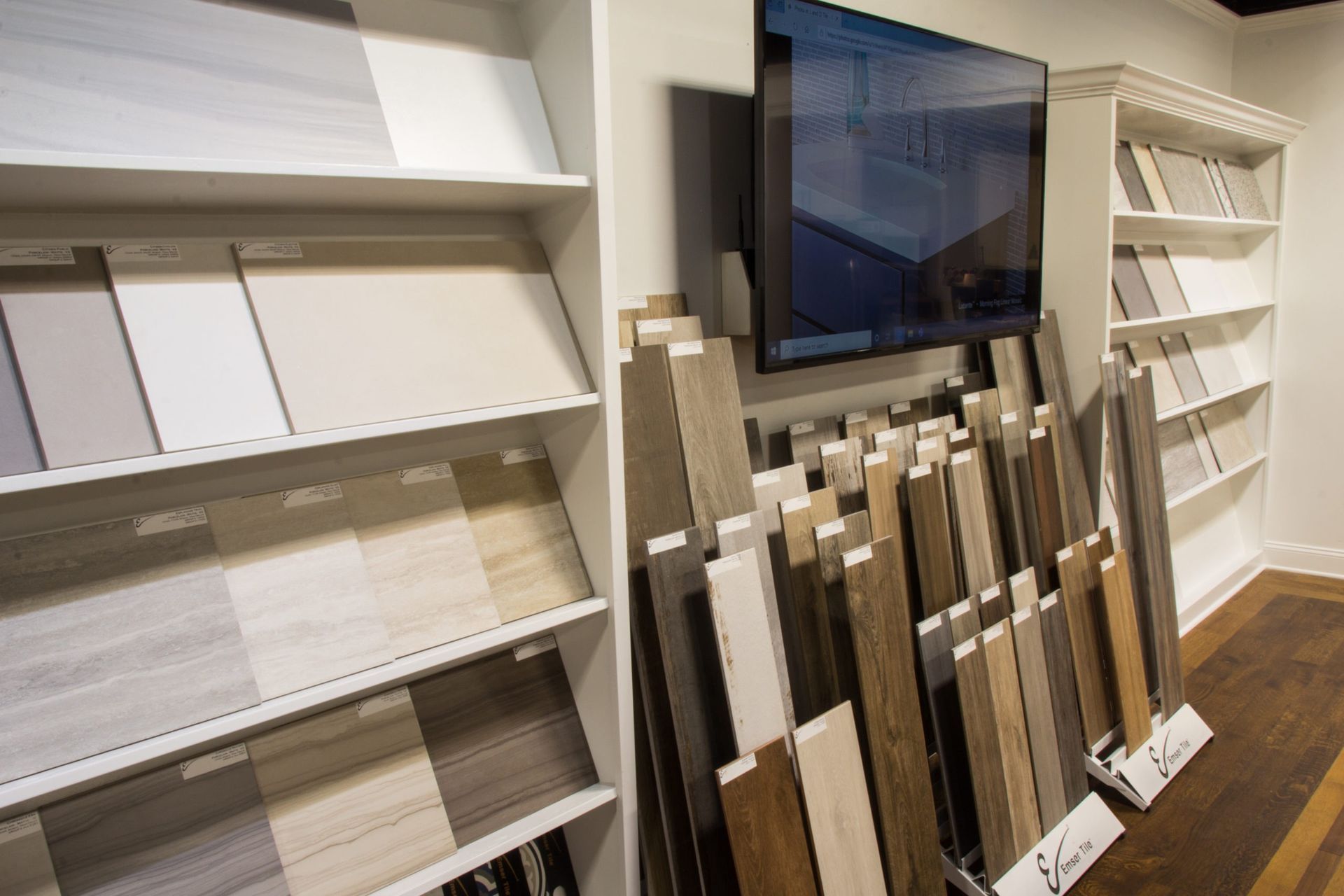Tile samples on shelves and display. A tv is mounted on the wall.