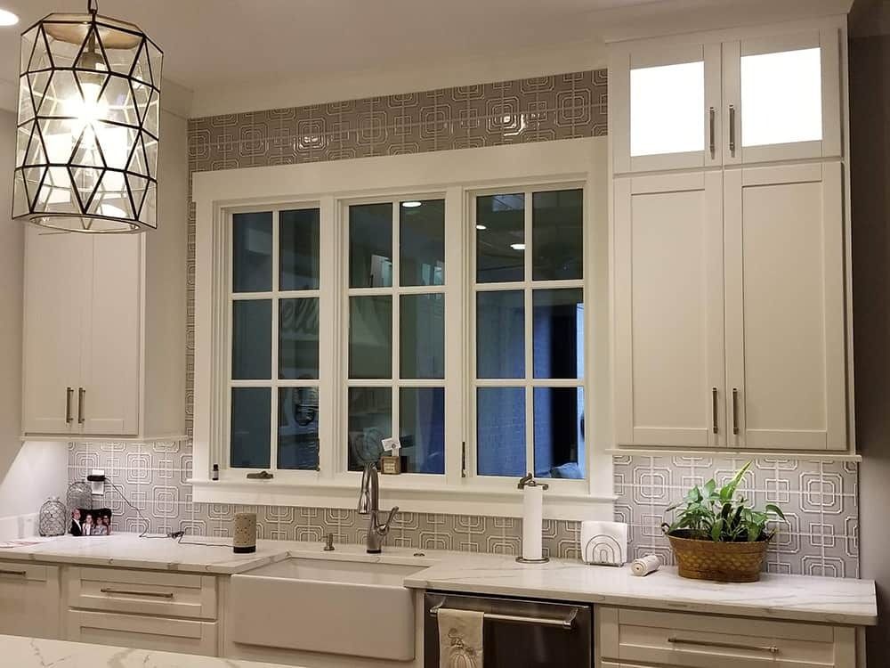 Kitchen with white cabinets, window, sink, and decorative backsplash.