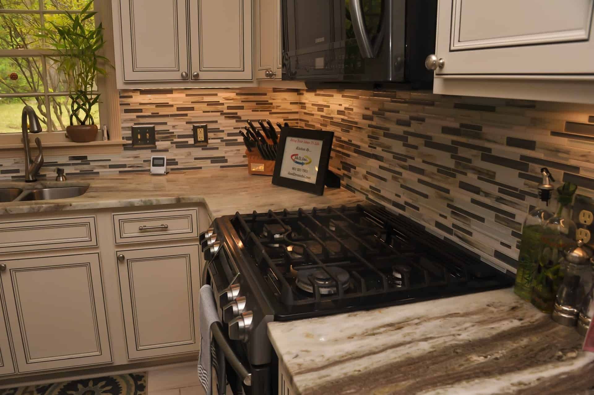 Kitchen with white cabinets, stone countertops, and a glass tile backsplash.