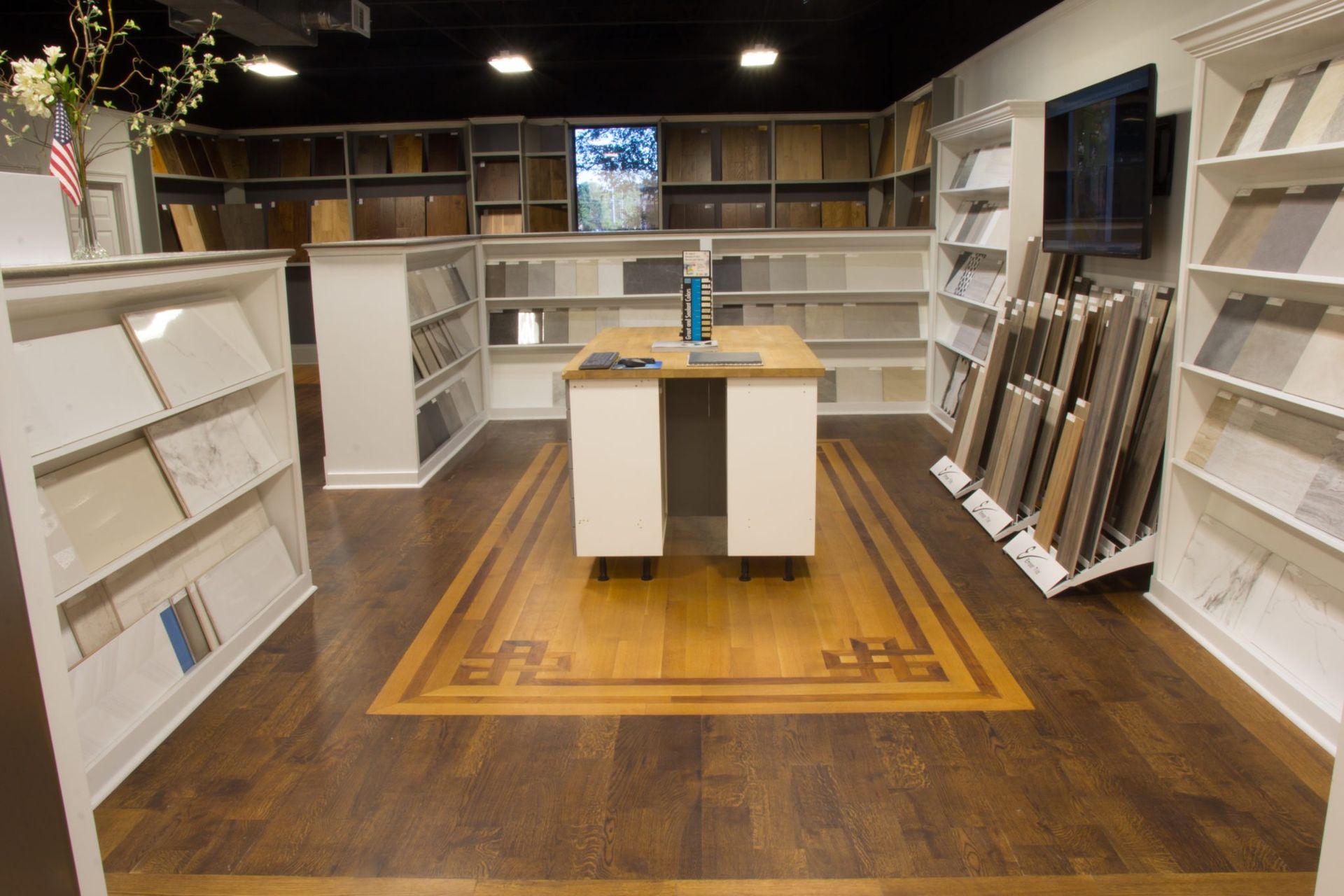 Showroom with wood and tile samples, display shelves, and a central display table.