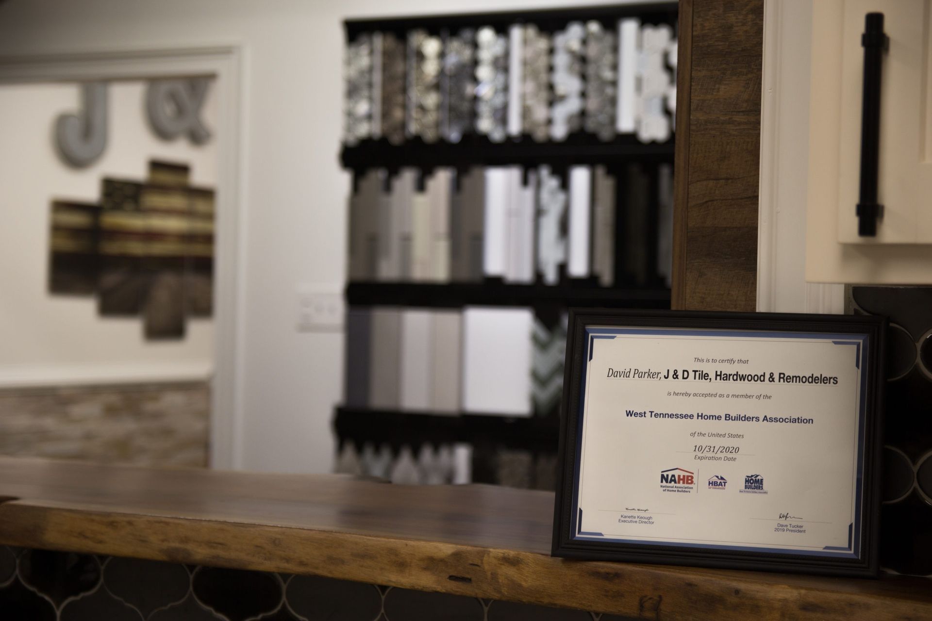A framed certificate on a wooden counter with a backsplash, samples and an open door.