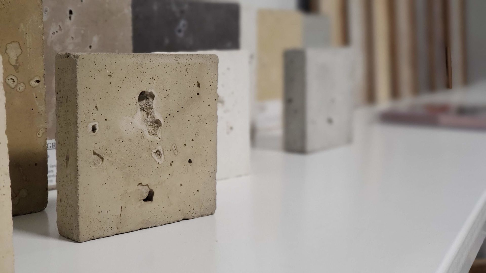 Concrete blocks of varying colors on a white shelf.