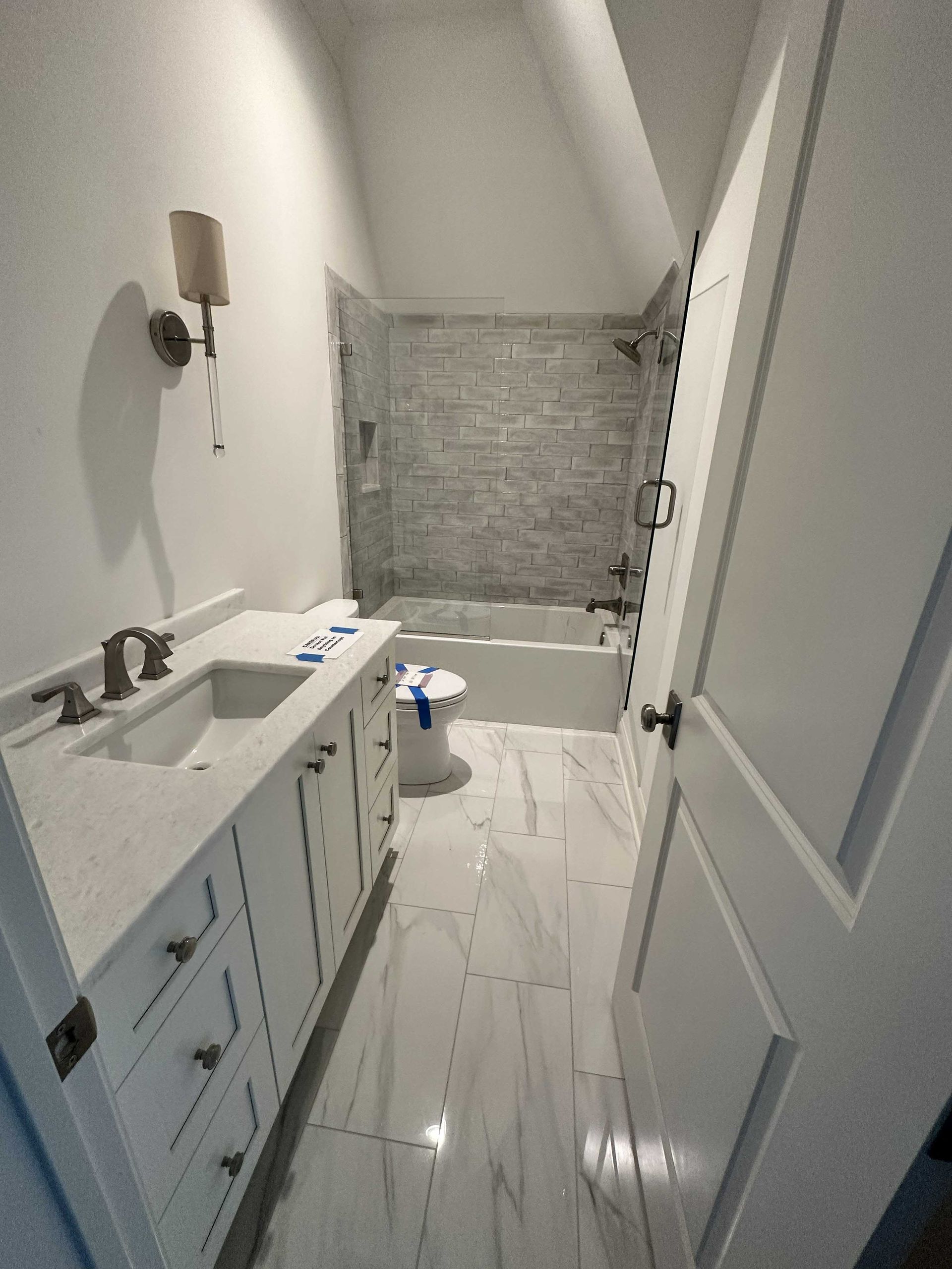 Bathroom with white vanity, marble-like floors, and stone-tiled shower wall.