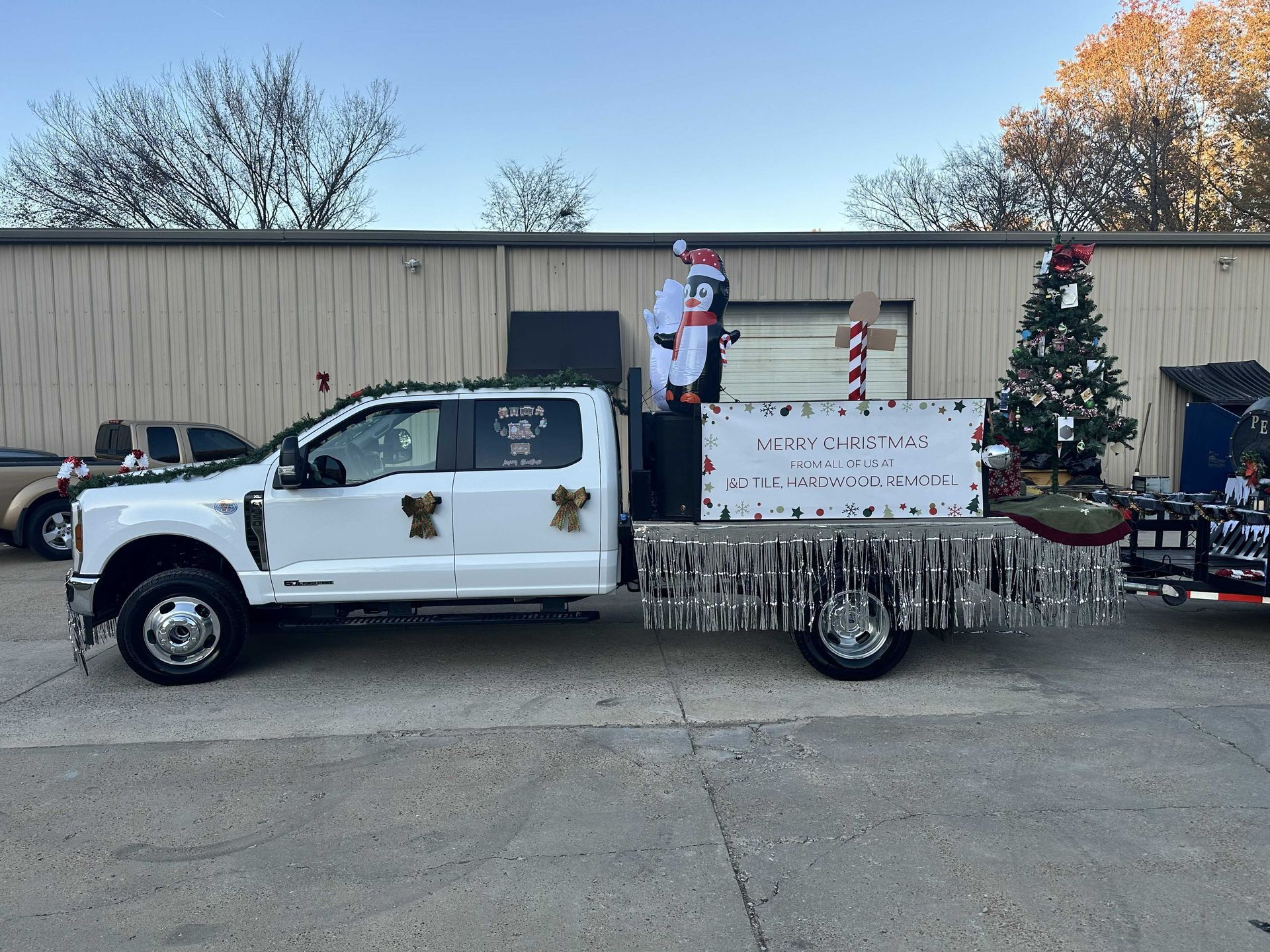 White truck decorated for Christmas parade, Santa figure, Christmas tree, and sign.