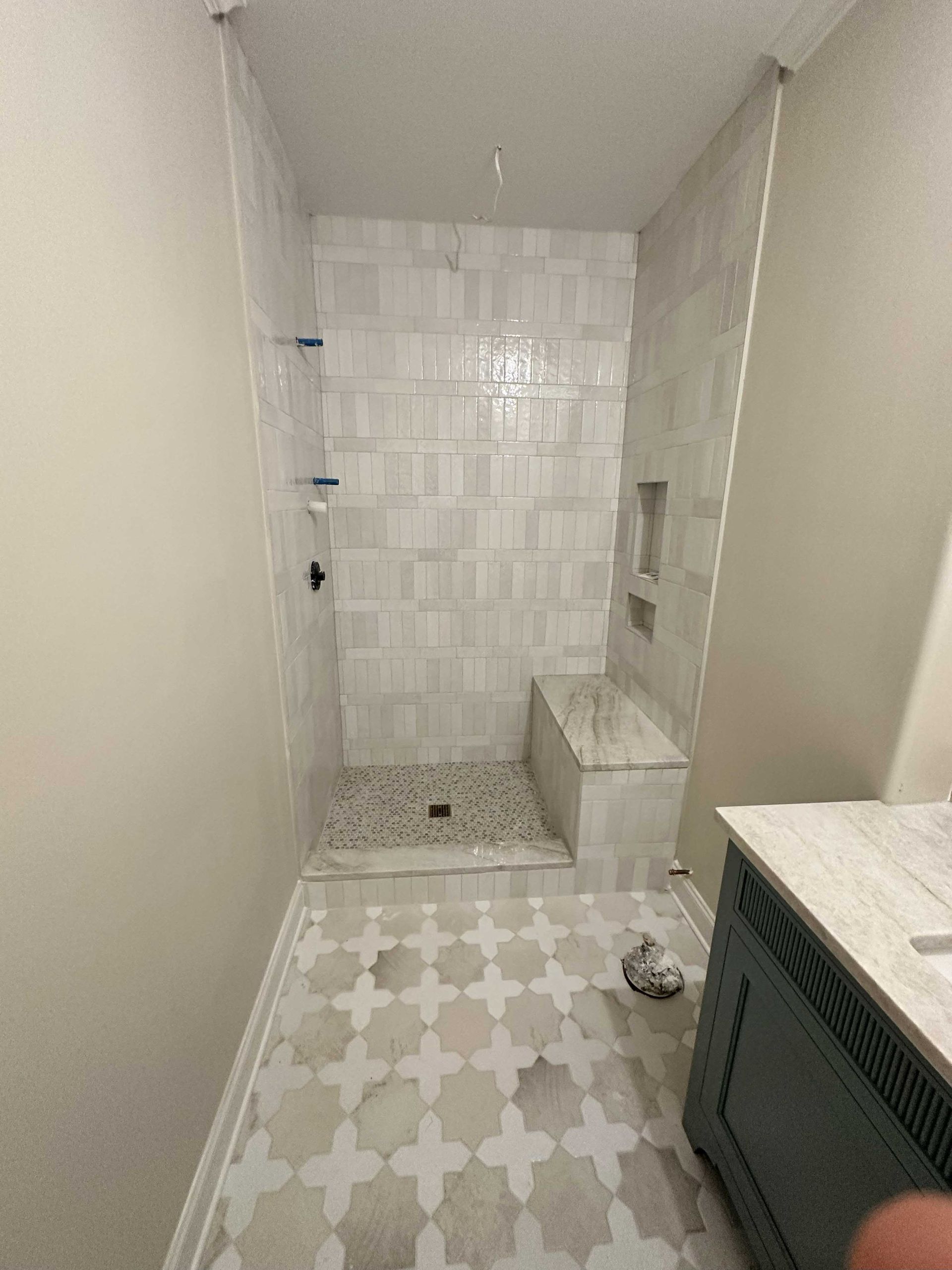 Finished tiled shower with a built-in bench and a patterned floor.