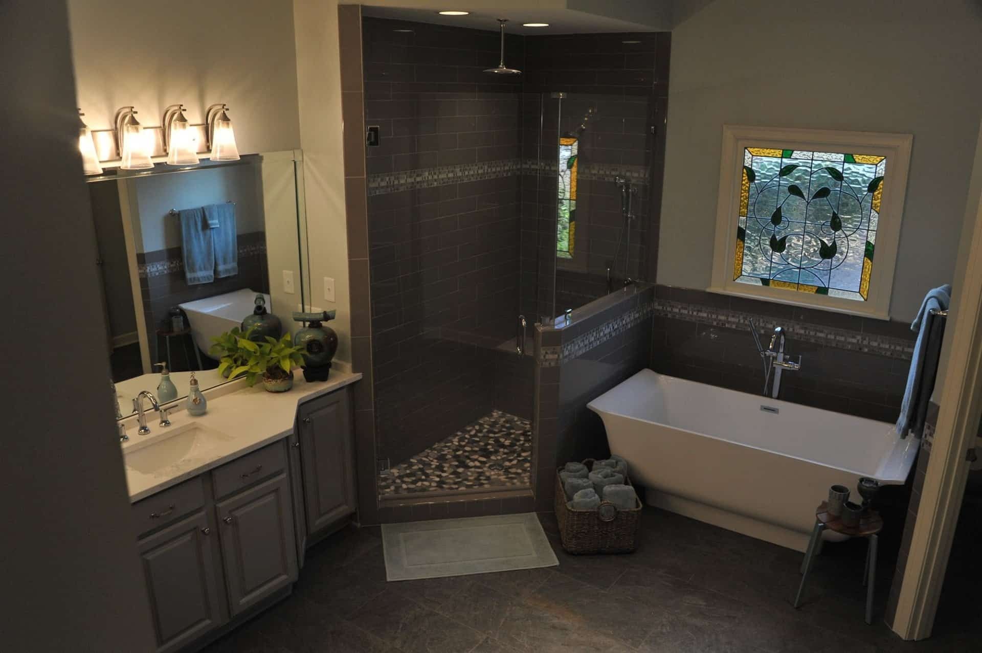 Bathroom with gray walls, white tub, glass shower, and stained glass window.