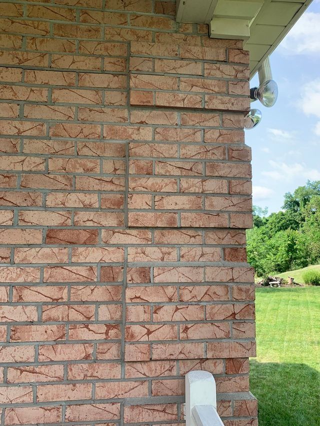 Brick exterior of a building, with several rectangular patches of brick.