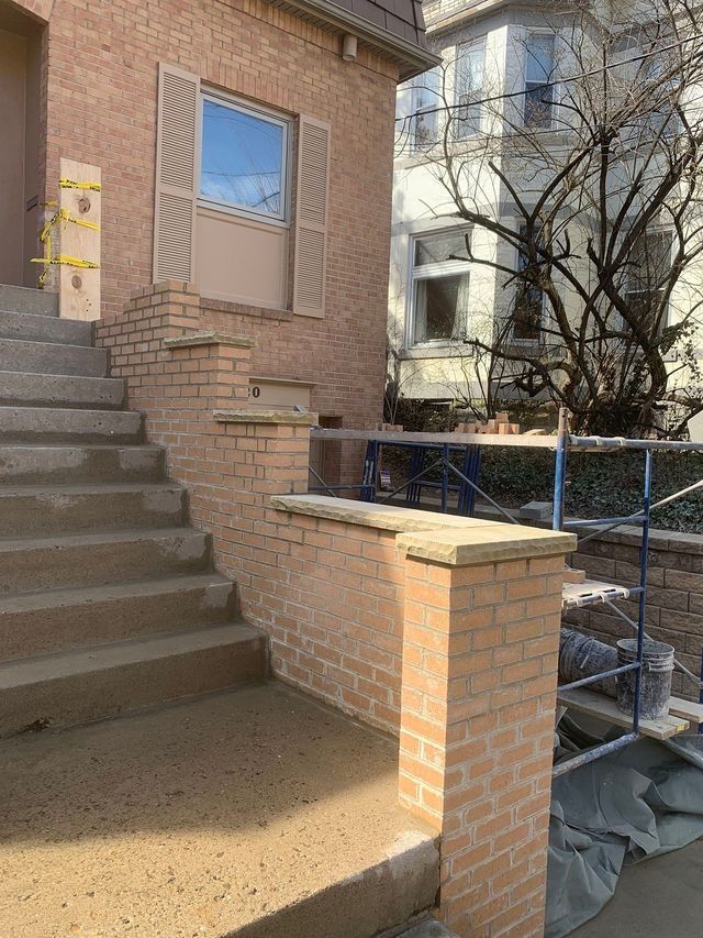 Brick steps and wall leading to a house entrance with a window. Scaffolding visible.