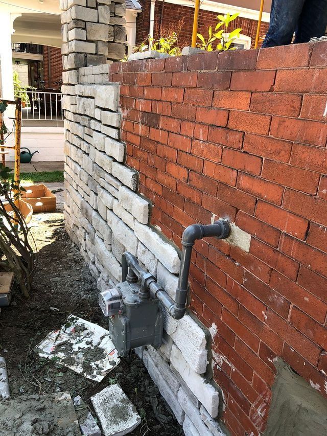 Exterior wall with brick and stone veneer being installed; gas meter and pipe.