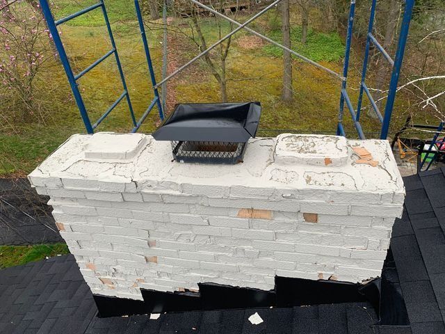 White brick chimney with black cap and flashing, on a roof.