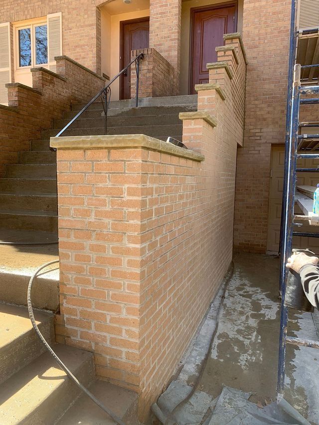 Brick wall and steps leading up to a building entrance. Light brown brick, stone accents.