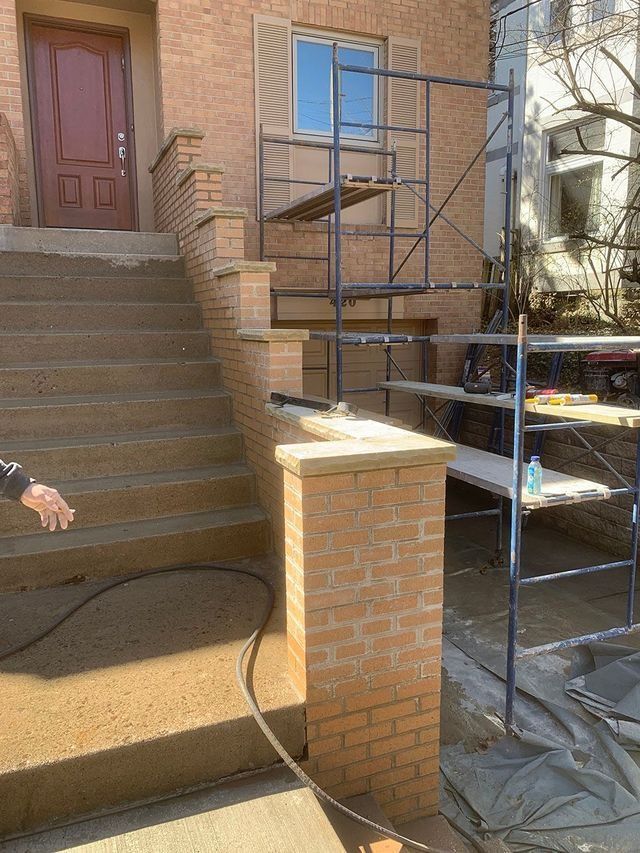 Brick steps leading to a house entrance with scaffolding set up for construction.