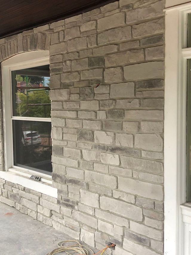 Stone facade with window, gray bricks, white trim.