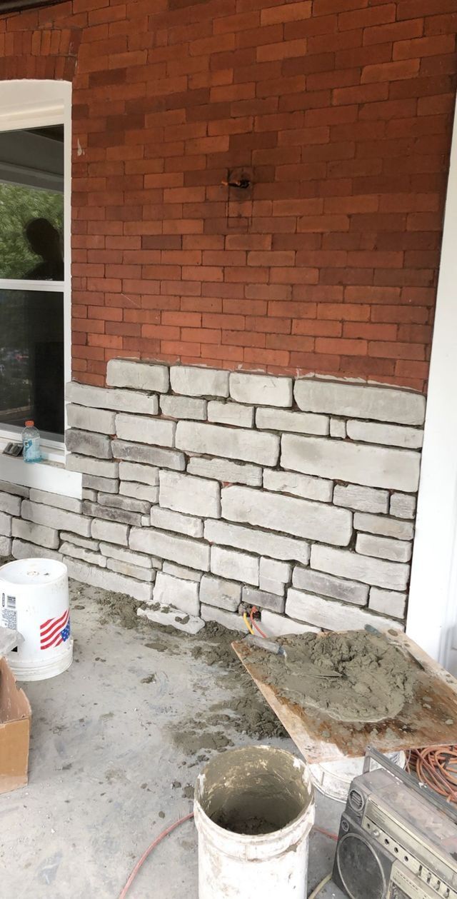 Brick home exterior under construction; stone veneer being applied.
