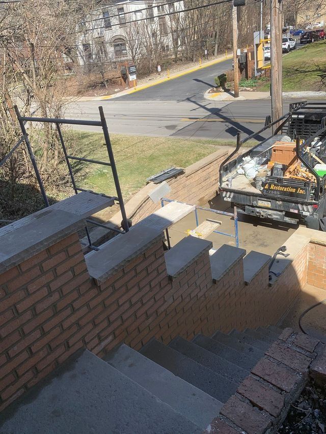 Brick steps lead to a street; a truck and scaffolding are visible on the side.