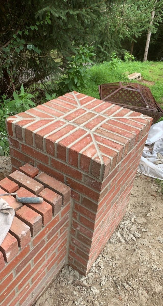Brick pillars being constructed outdoors, showcasing bricklaying patterns.