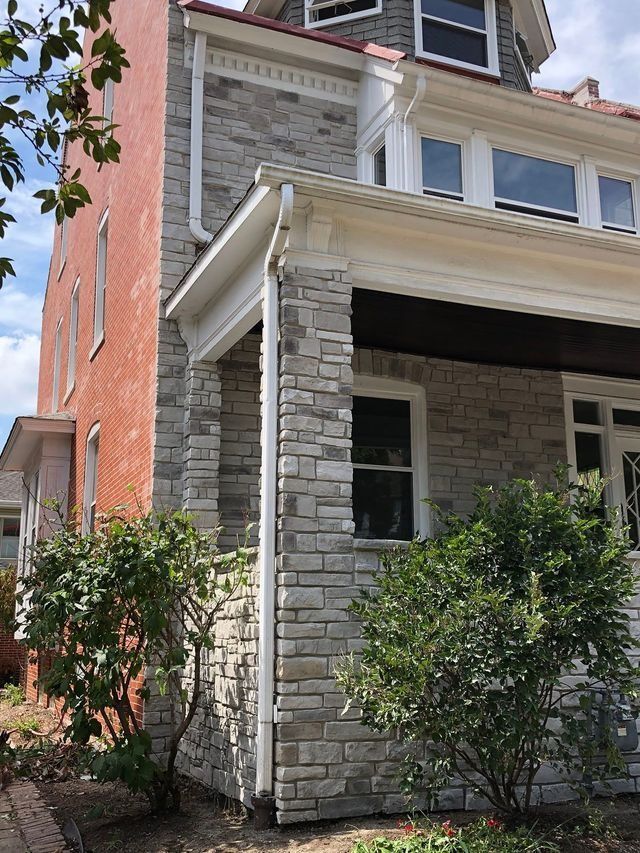 Brick and stone house exterior with bushes.